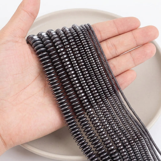 Black hematite rondelle beads in multiple sizes shown on hand for scale