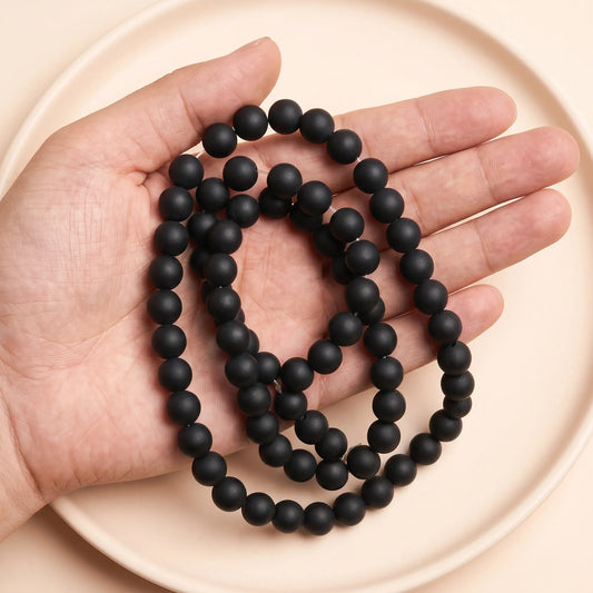 Matte black onyx beads shown in hand for size comparison