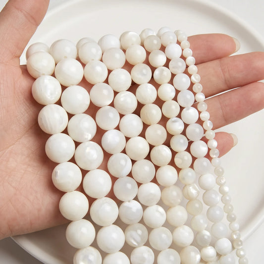 Mother of pearl beads shown in hand for size comparison