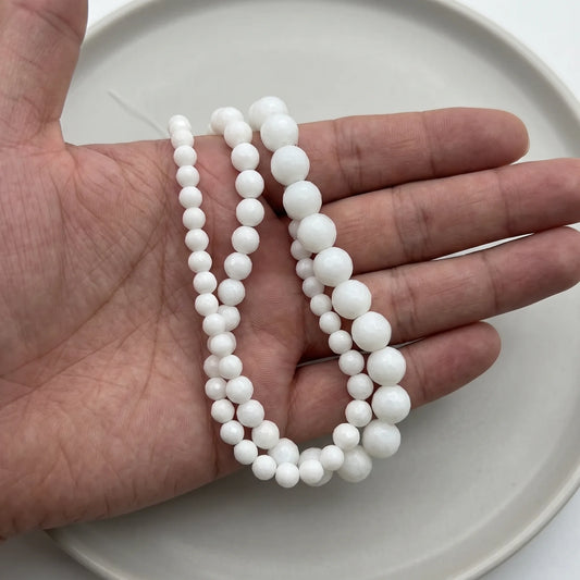 white faceted onyx stone beads in hand