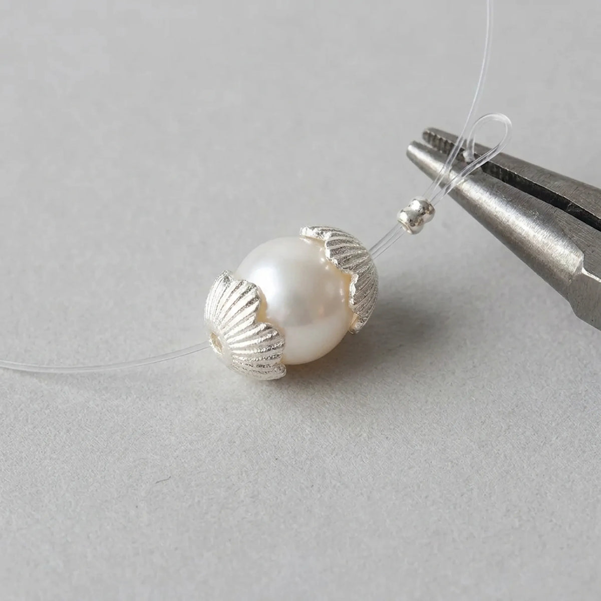 Sterling silver flower bead caps framing a pearl bead in jewelry making