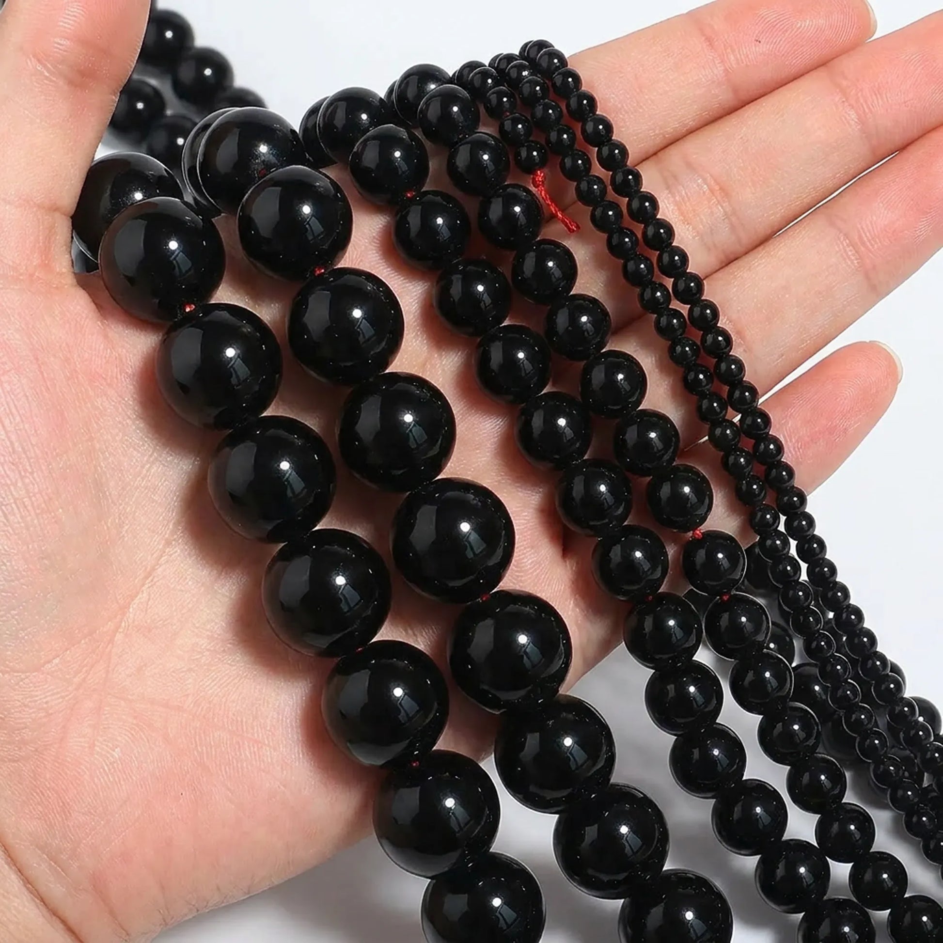 Natural black agate beads shown in hand for size comparison