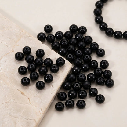 Close-up of black round glass pearl beads for jewelry making with pearl coated finish