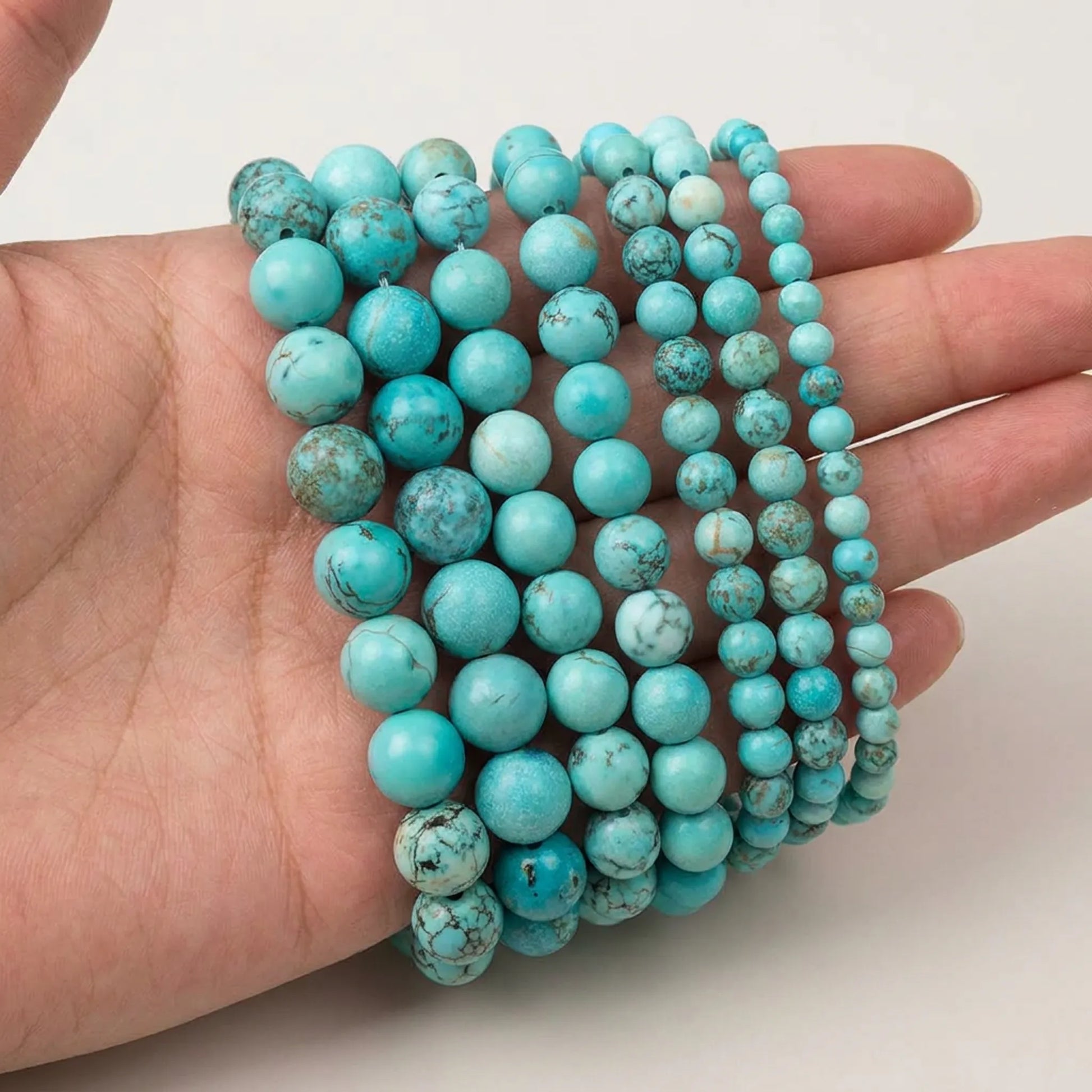 Natural blue turquoise beads shown in hand for size comparison