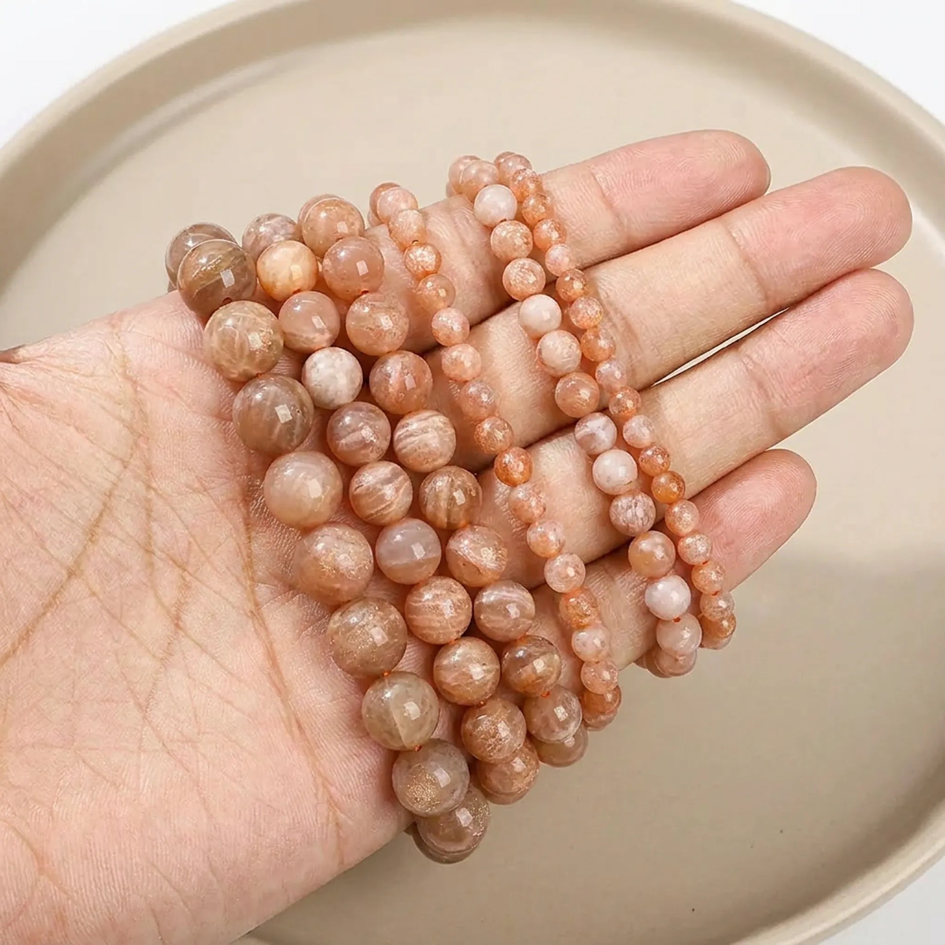 Brown sunstone beads shown in hand for size comparison