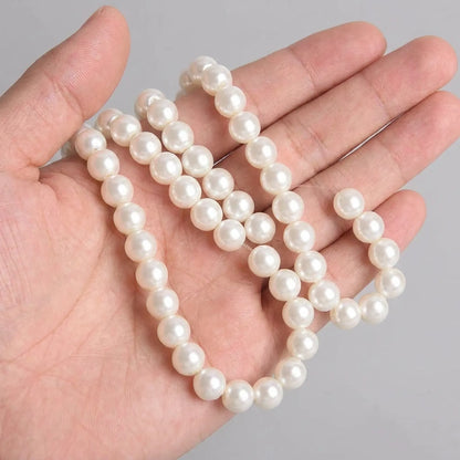 Cream glass pearl round beads shown in hand for size comparison