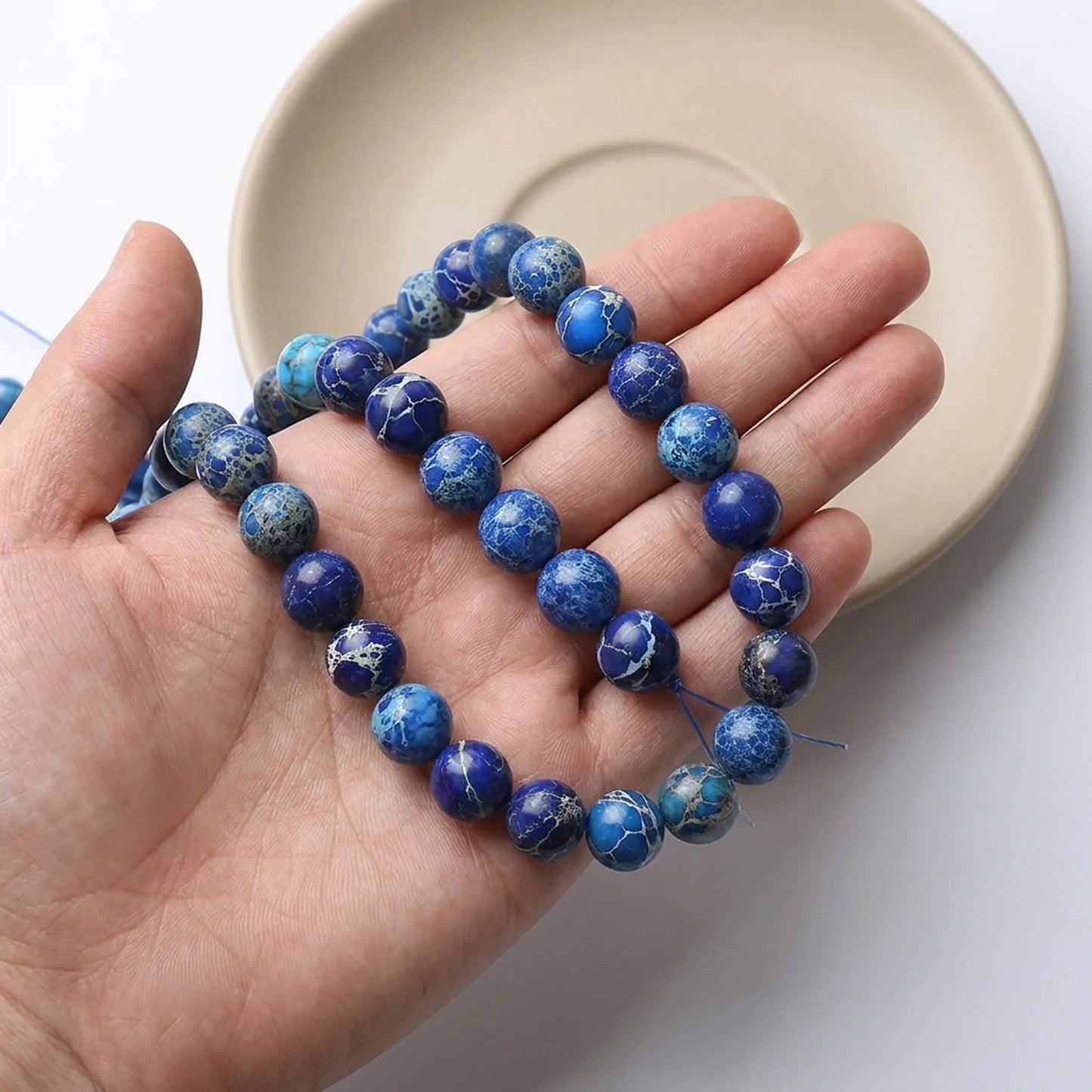 Dark blue sea sediment jasper beads shown in hand for size comparison