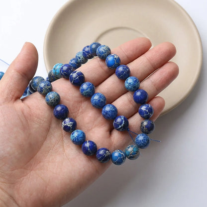 Dark blue sea sediment jasper beads shown in hand for size comparison