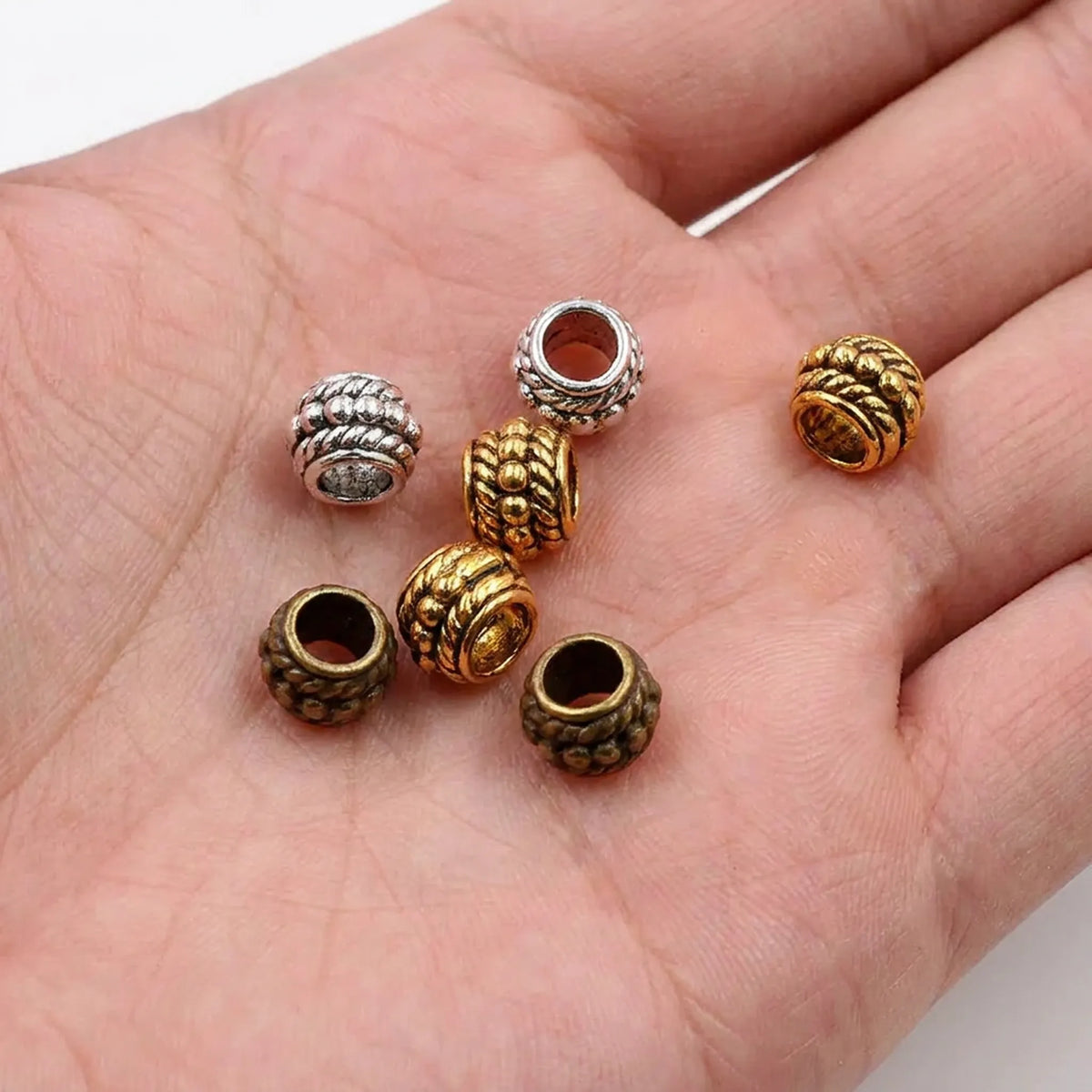 Decorative barrel spacer beads shown in hand for size comparison