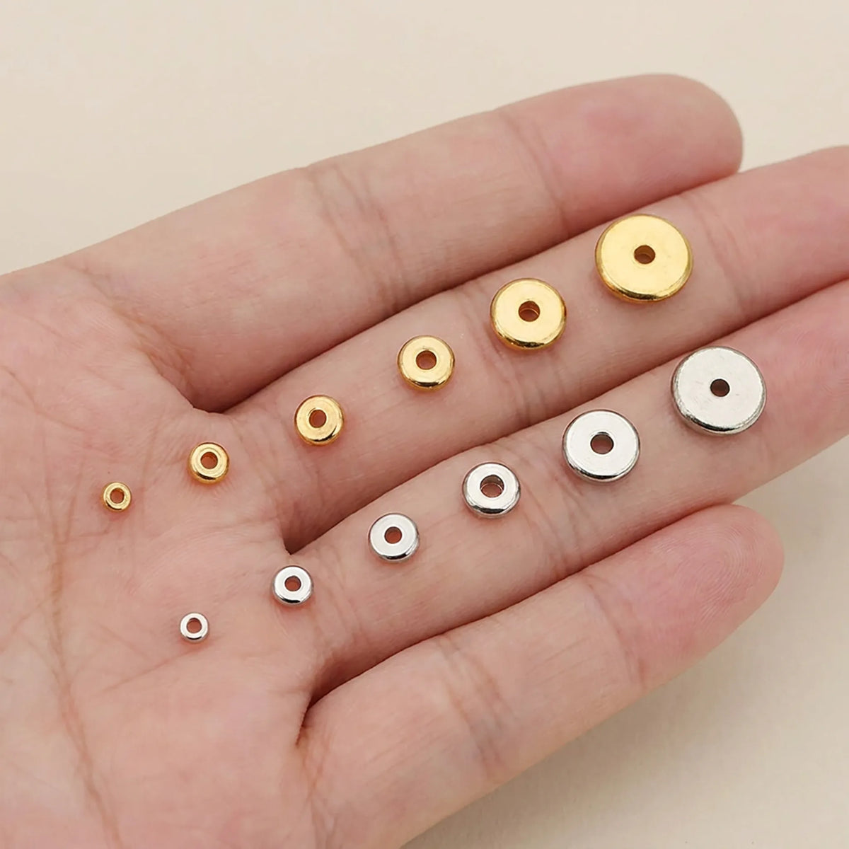 Flat round spacer beads shown in hand for size comparison