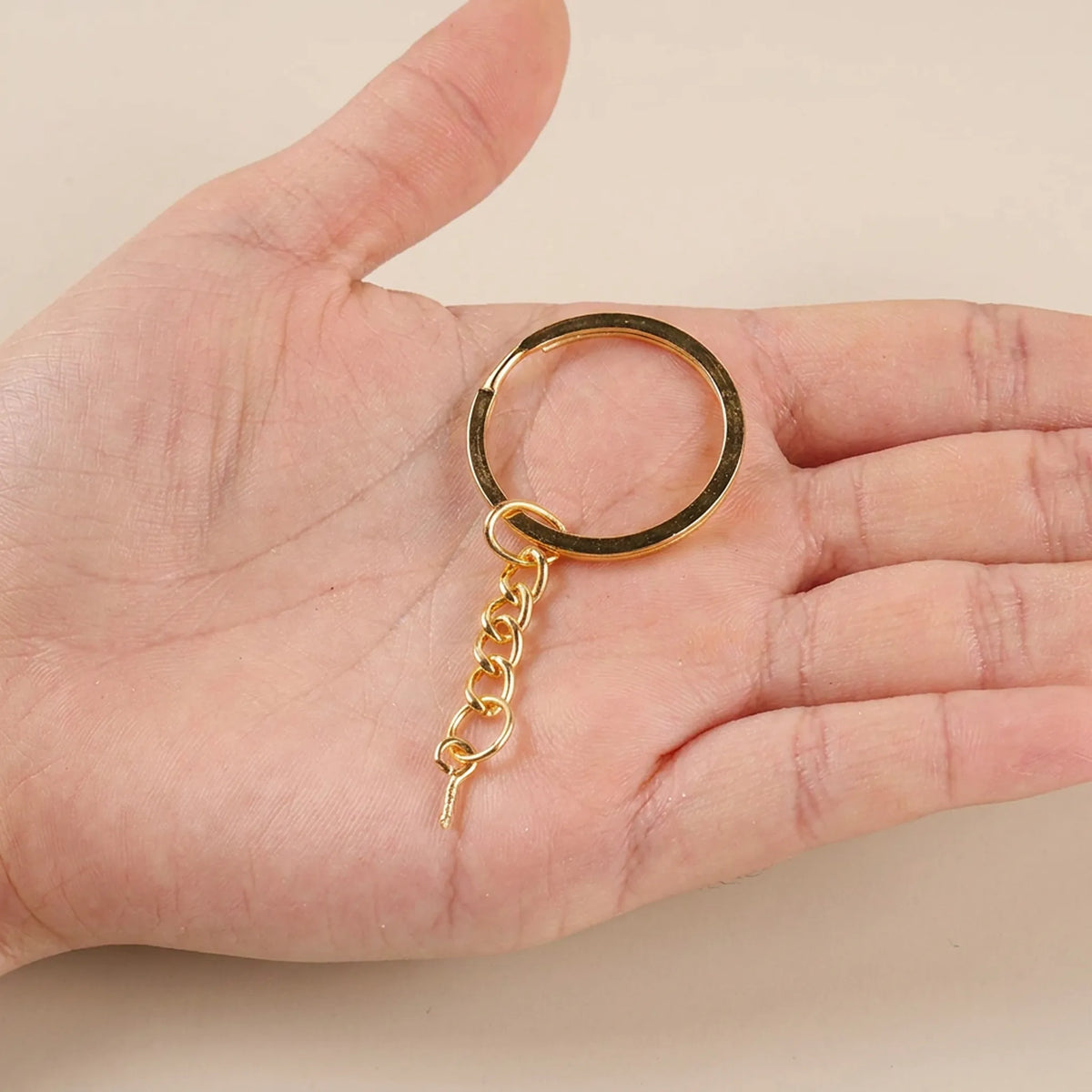 Gold split key ring with eye screw and chain shown in hand for size reference