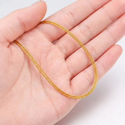 Gold color stainless steel beading wire shown on hand for size reference