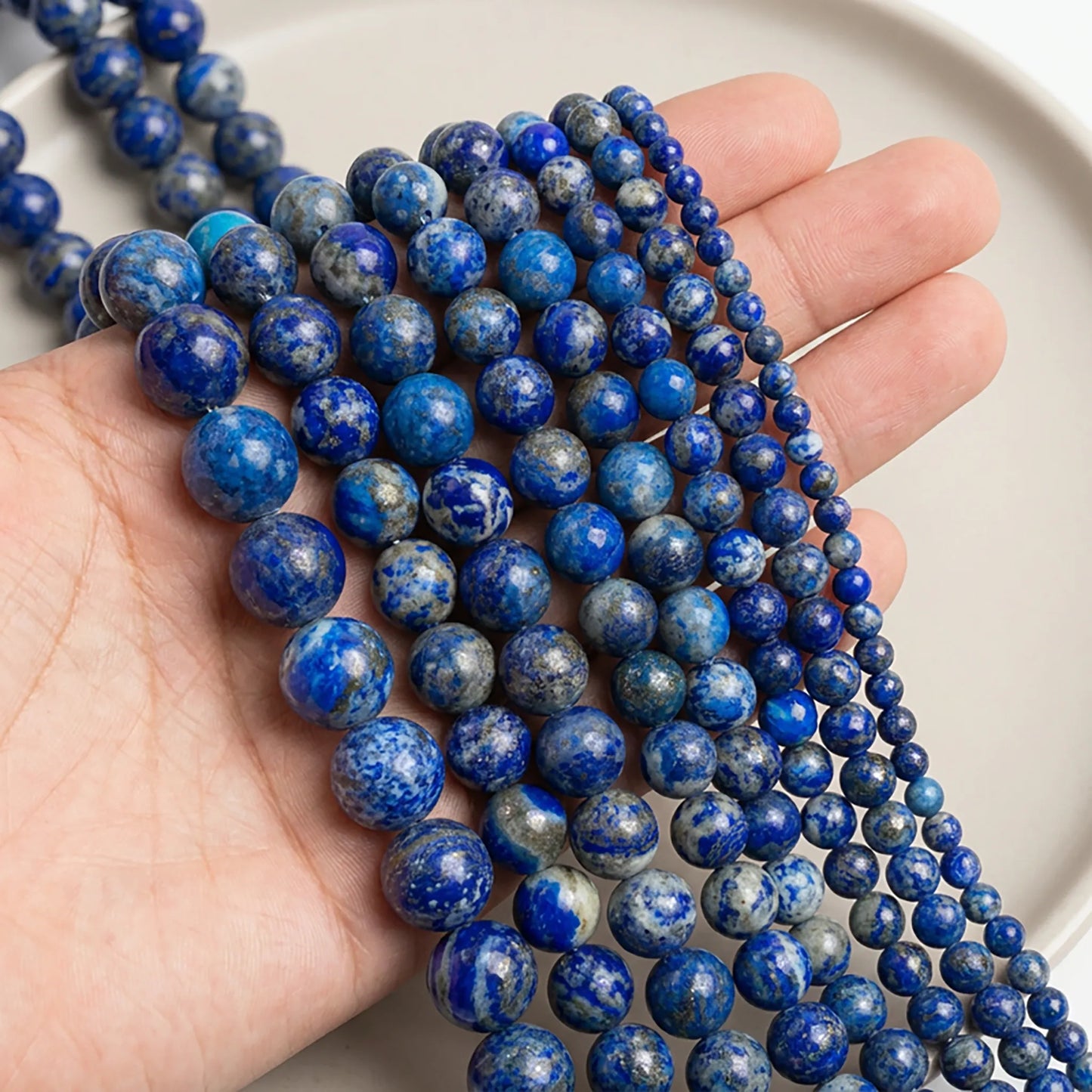 Natural lapis lazuli beads shown in hand for size comparison