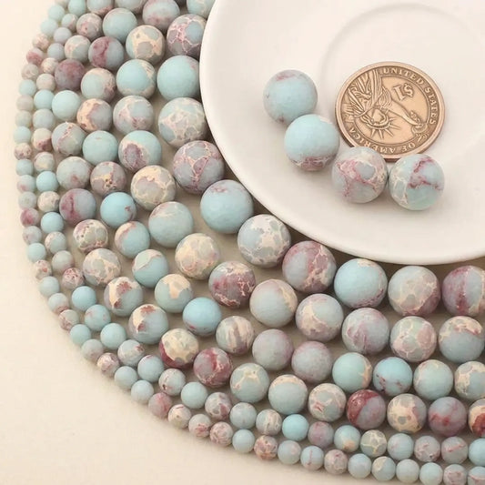 Matte Shoushan stone beads in multiple sizes shown with coin for size comparison