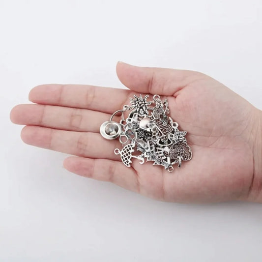Mixed silver tone charms shown in hand for size reference