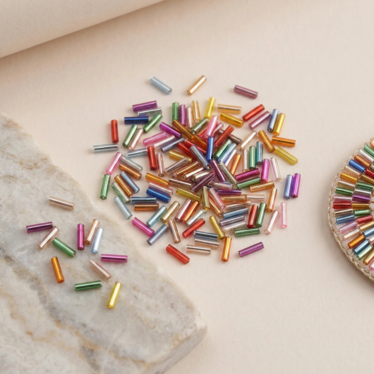 Mixed color 2x6mm long tube lined cylinder glass seed beads displayed with jewelry making materials