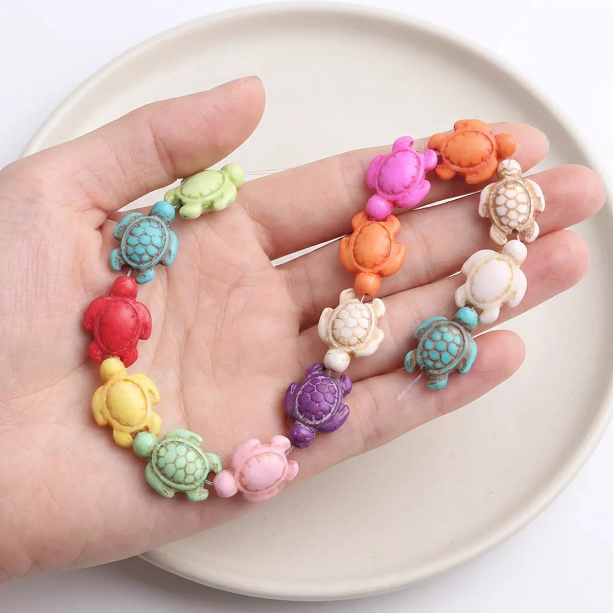 Mixed color carved turtle howlite beads 14x18mm shown in hand for scale