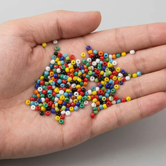 Mixed opaque 2mm glass seed beads shown in hand assorted colorful seed beads for jewelry making