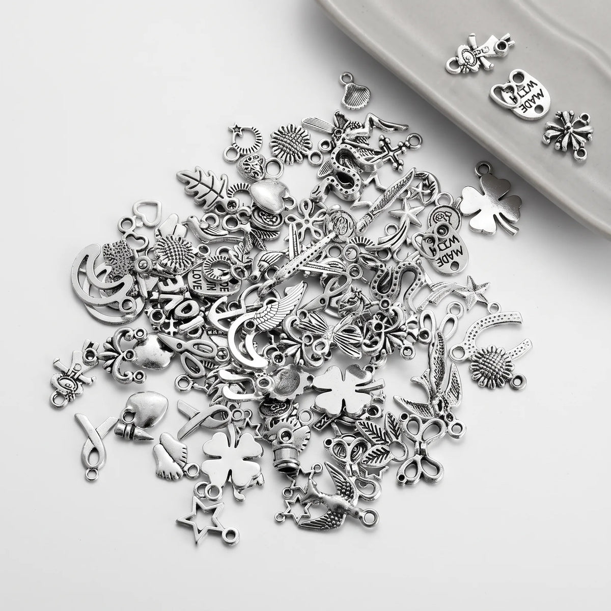 Mixed silver tone jewelry charms with assorted flowers, stars, leaves and decorative designs