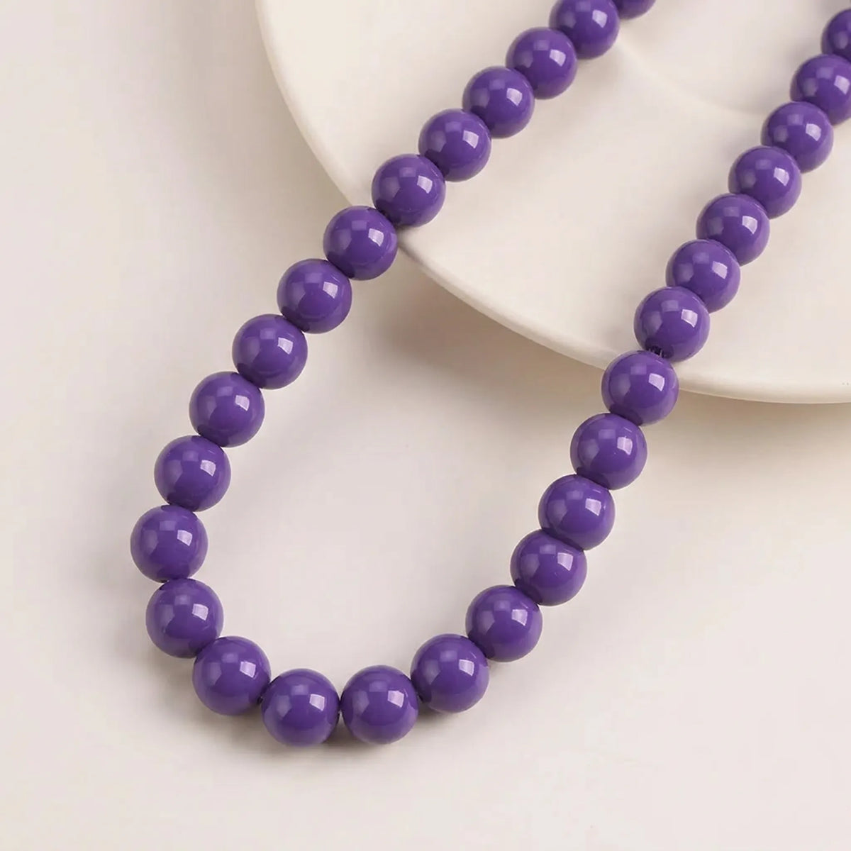 Opal purple coated glass round beads arranged on a 16 inch strand
