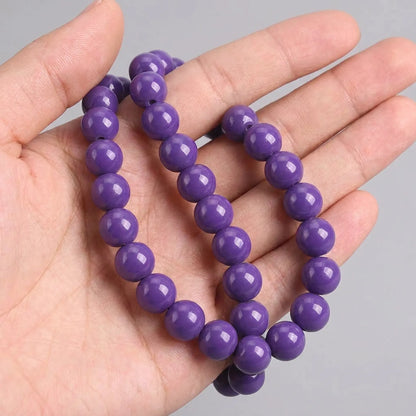 Opal purple coated glass round beads shown in hand for size reference