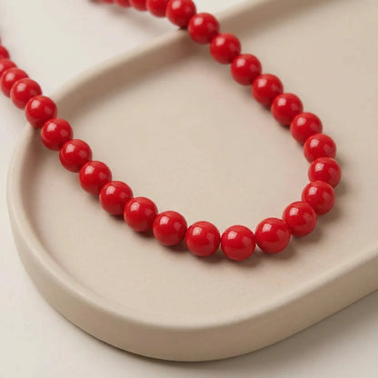 Close up of red coated glass round beads on a ceramic tray