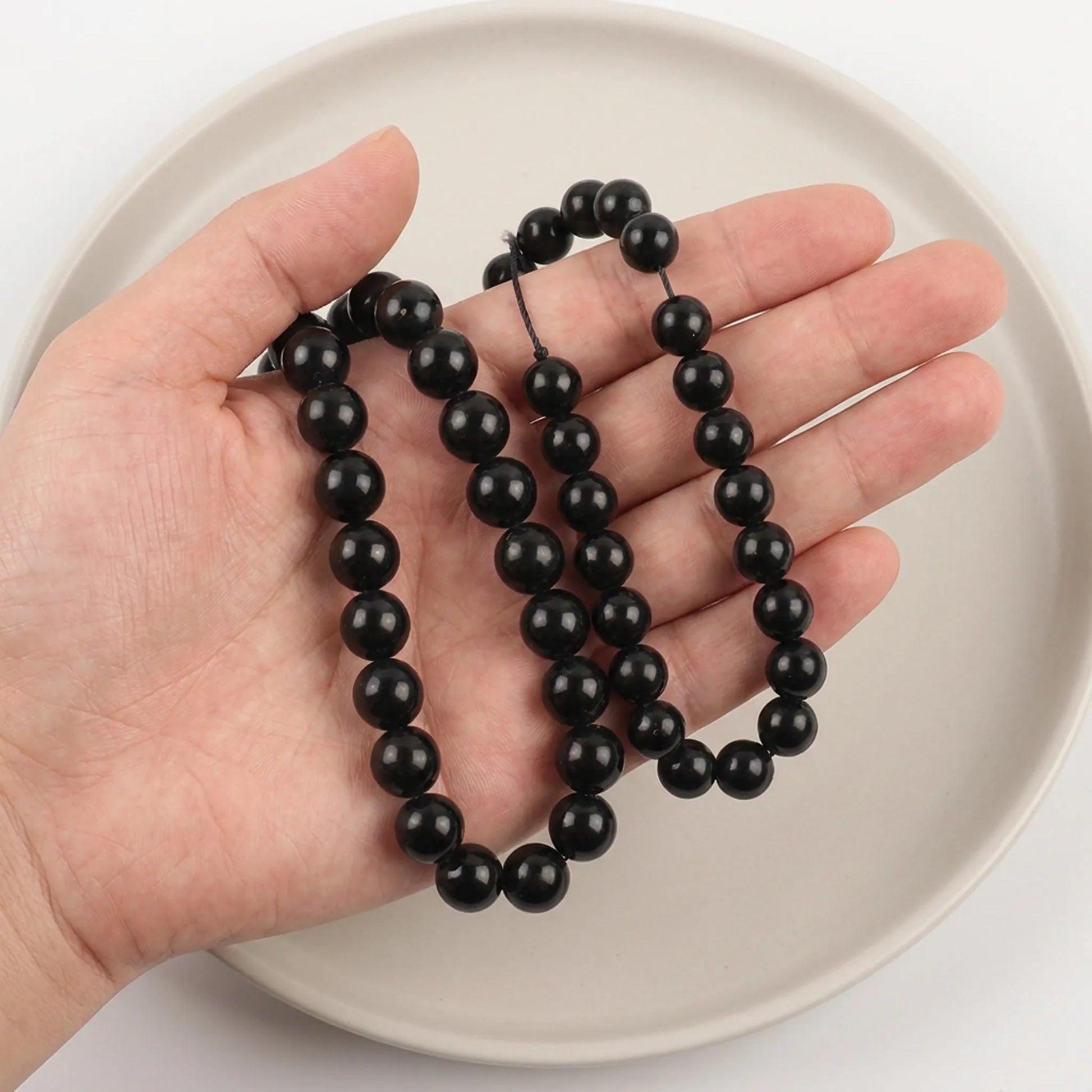 Shungite beads shown in hand for size comparison