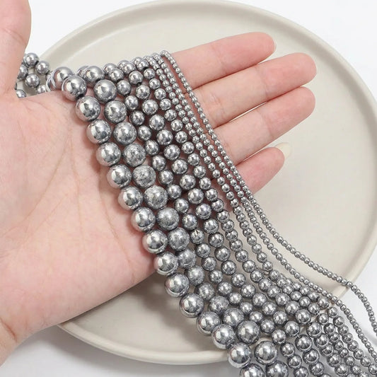 Silver hematite beads shown in hand for size comparison