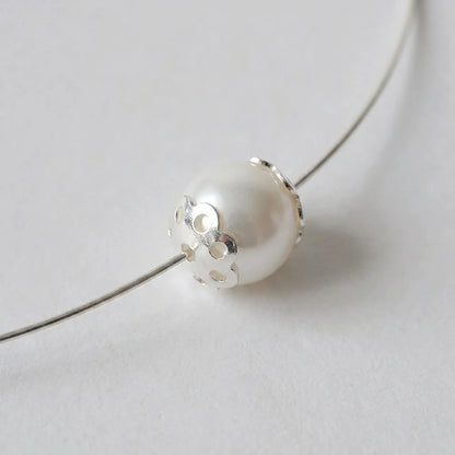 Sterling silver flower bead cap fitted against a pearl bead on jewelry wire