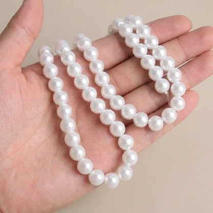 White glass pearl round beads shown in hand for size comparison