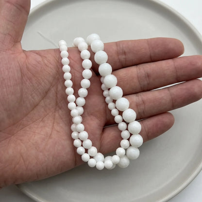 white faceted onyx stone beads in hand