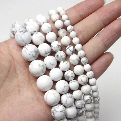 White turquoise howlite beads shown in hand for size comparison