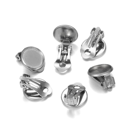 A collection of stainless steel round flat ear clip bases of various sizes, displayed on a white background.